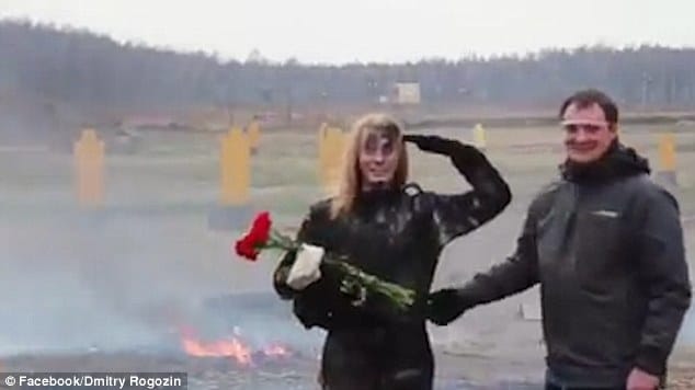 A man comes to congratulate her with a bunch of red flowers. The pair then laugh and salute before walking off together